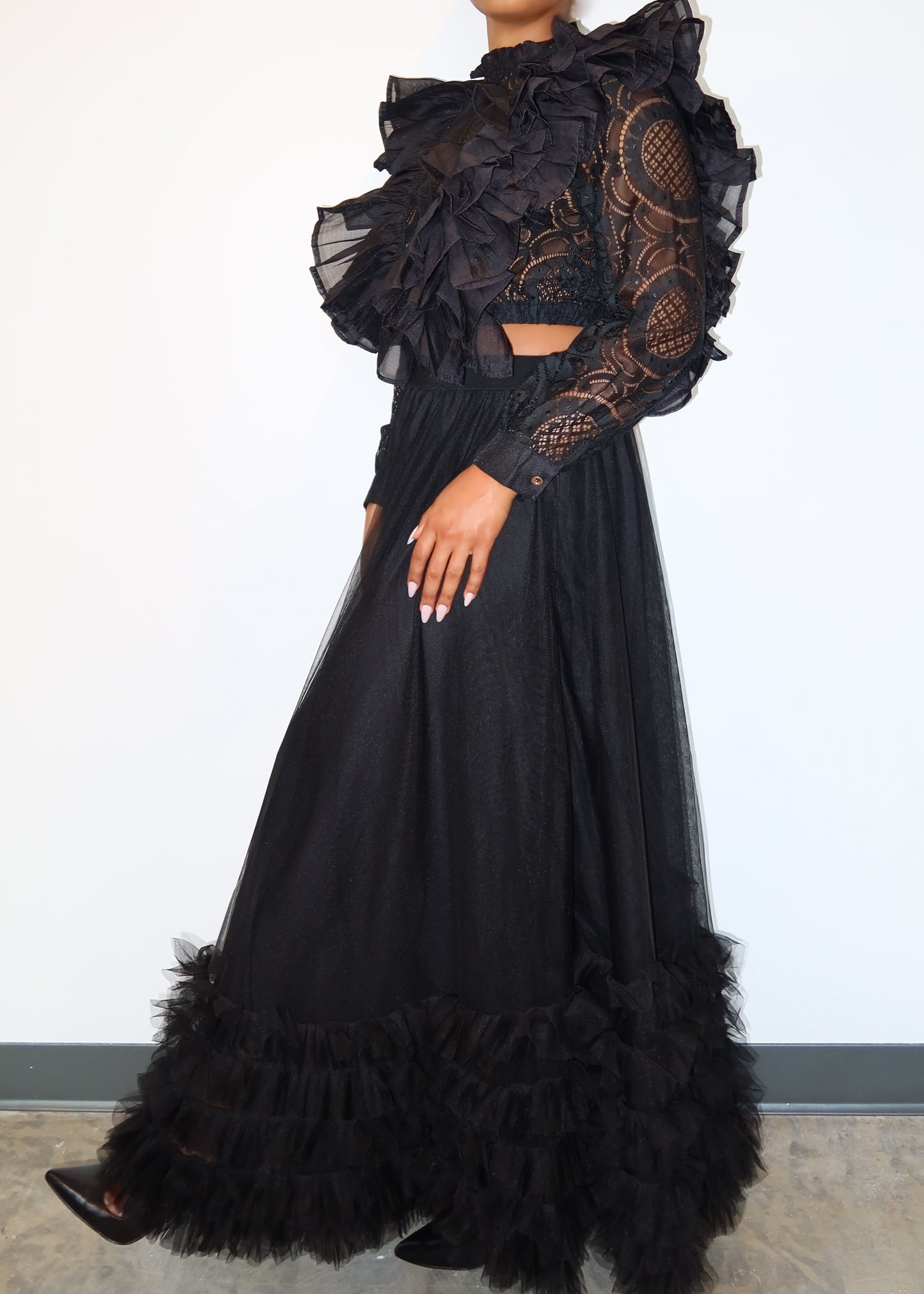 Luxury evening wear set
Fashion-forward gala outfit
Runway-inspired street style
Elegant black formal wear
Editorial fashion aesthetic
Sheer lace and ruffle details
High-neck dramatic crop top
Voluminous tulle maxi skirt
Statement ruffled hemline
Vintage-meets-modern silhouette
Dramatic all-black two-piece set
Gothic Victorian-inspired fashion
High-fashion statement outfit
Edgy ruffle crop top & maxi skirt
Avant-garde black couture