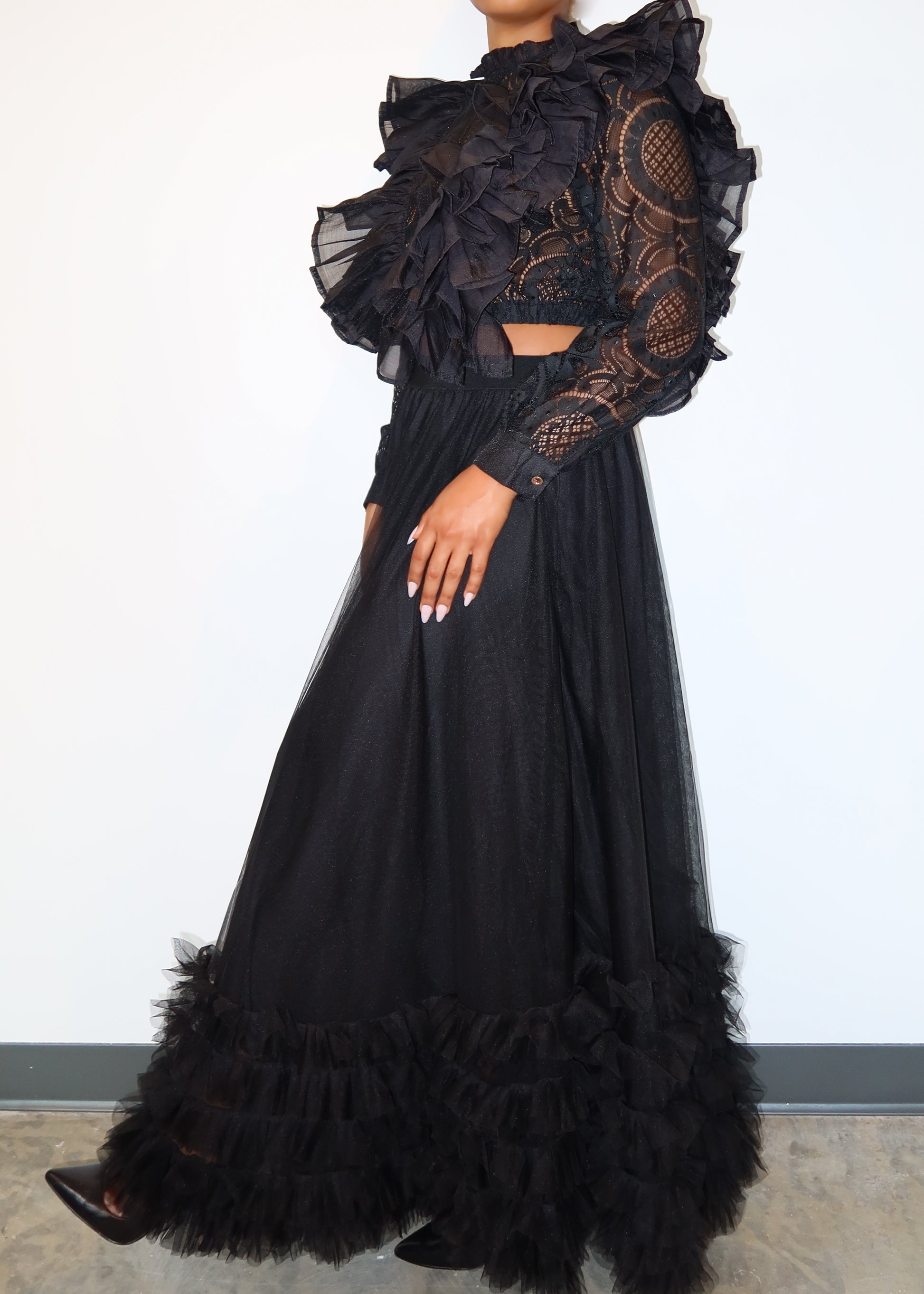 Luxury evening wear set
Fashion-forward gala outfit
Runway-inspired street style
Elegant black formal wear
Editorial fashion aesthetic
Sheer lace and ruffle details
High-neck dramatic crop top
Voluminous tulle maxi skirt
Statement ruffled hemline
Vintage-meets-modern silhouette
Dramatic all-black two-piece set
Gothic Victorian-inspired fashion
High-fashion statement outfit
Edgy ruffle crop top & maxi skirt
Avant-garde black couture