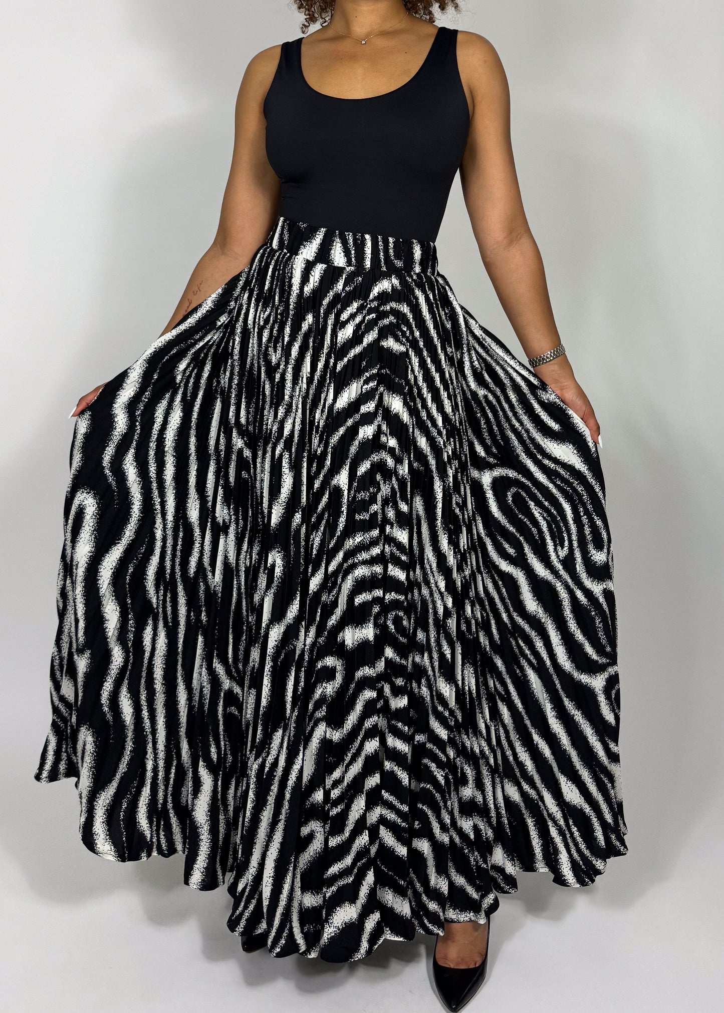 Zebra print skirt
Animal print maxi skirt
High-waisted full skirt
Flowy A-line skirt
Black and white statement skirt
Bold patterned skirt
Long pleated skirt
Wide hem maxi skirt
Boho chic
Glamorous fashion
Edgy elegance
Statement fashion
Fashion-forward outfit
Retro-inspired style
Sophisticated and bold
High-waisted dramatic skirt
Timeless monochrome 